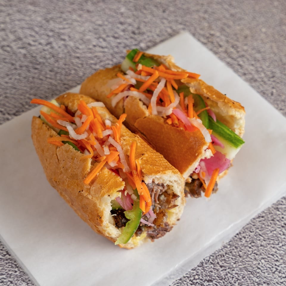 Braised beef dip banh mi with pickled vegetables and jalapeno.